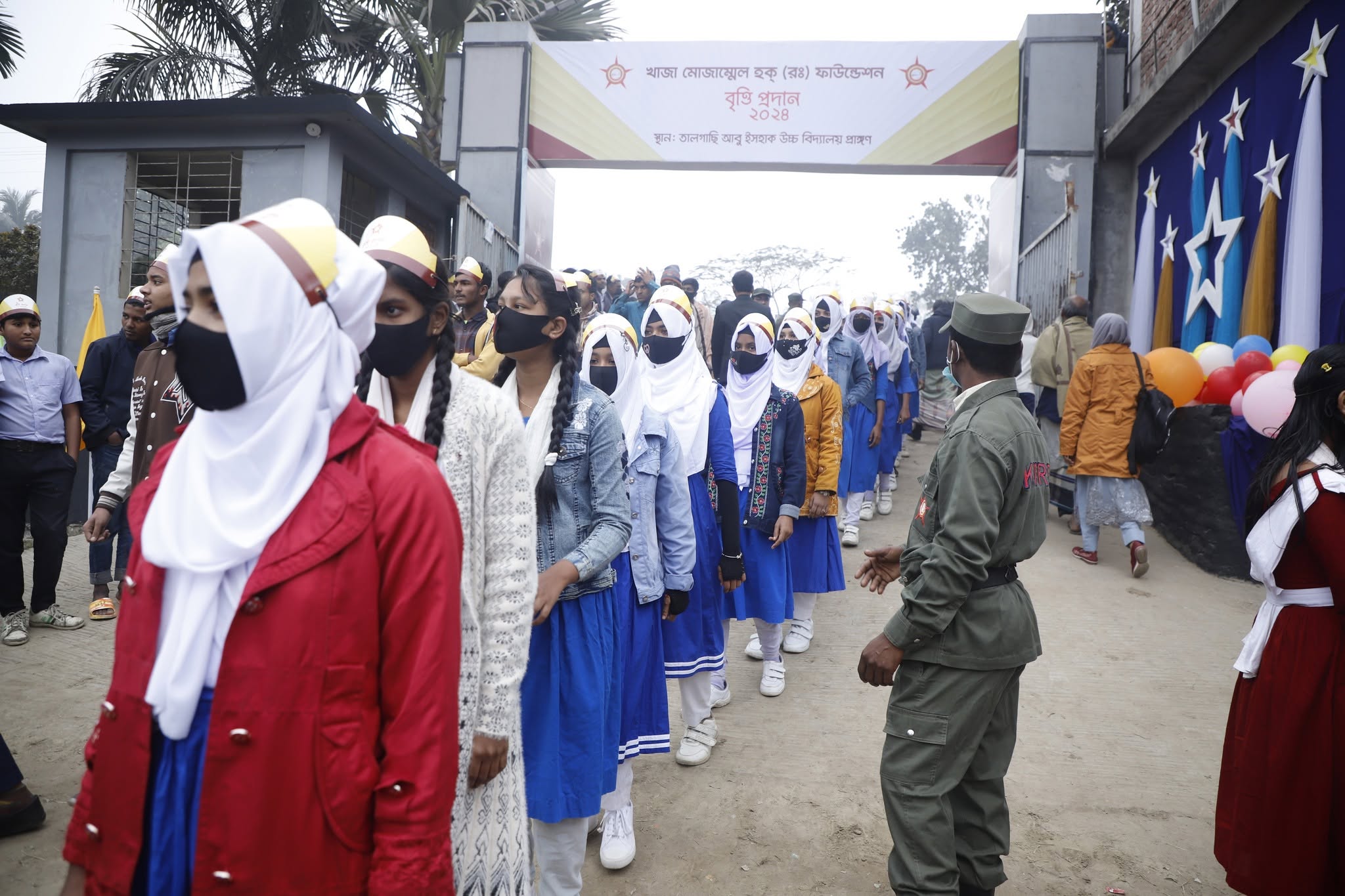 Participants entering beneath a Bengali scholarship award banner marked 2024.