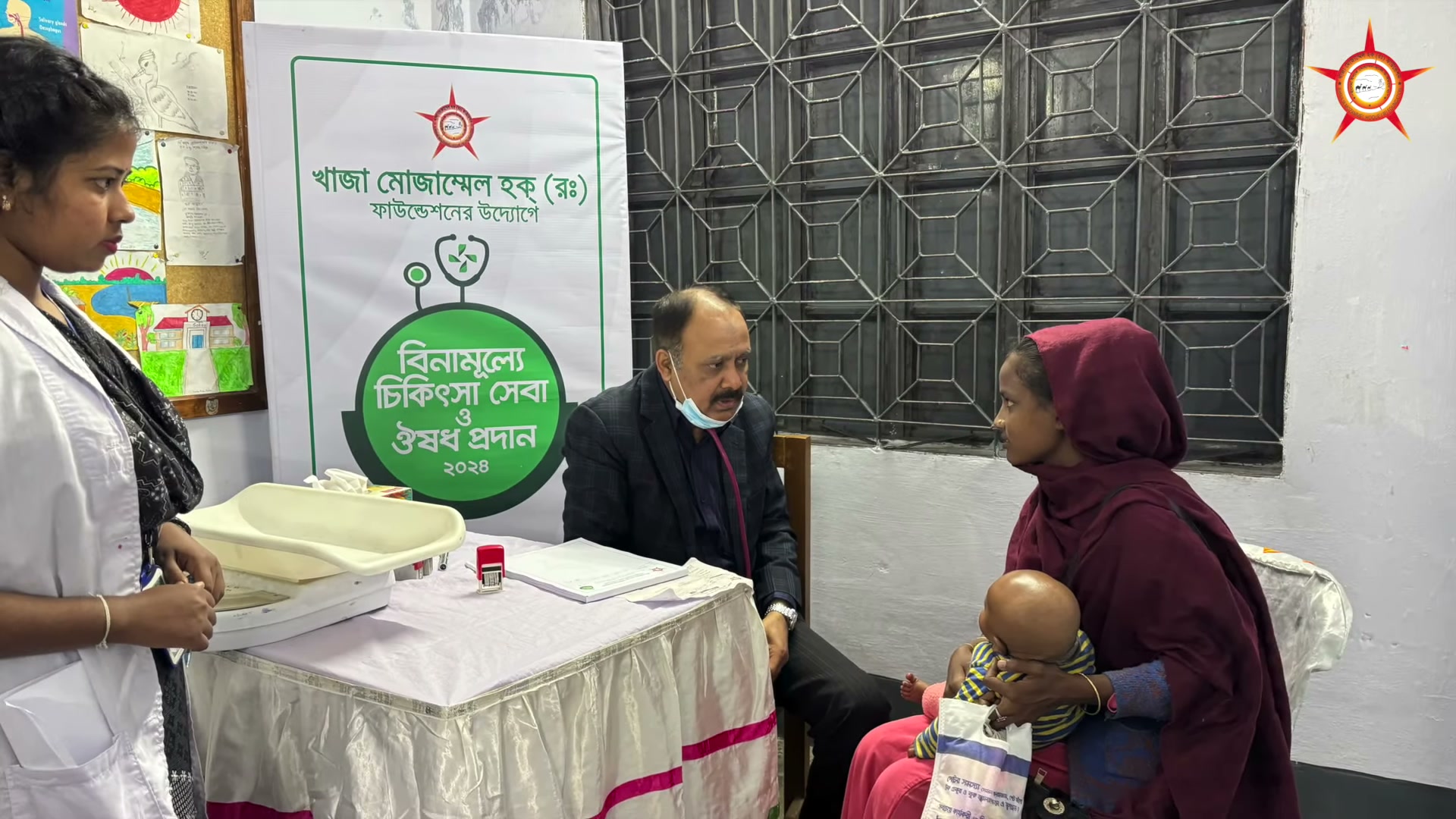 A consultation scene: a woman holding a child at a table during the medical camp.