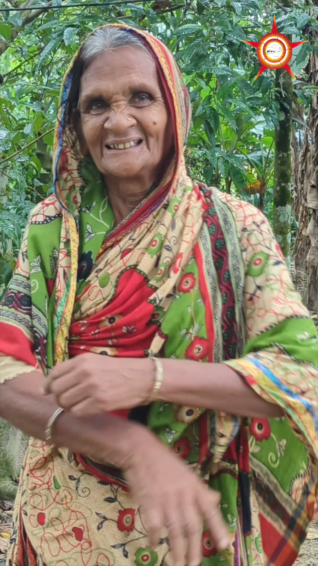 The participant introduced as Amirjan Bibi smiling outdoors among trees.