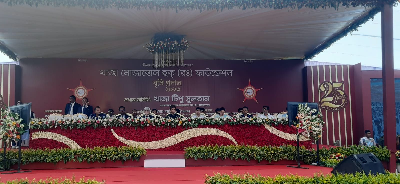 The stage dressed in flowers, with the banner বৃত্তি প্রদান ২০২৬.