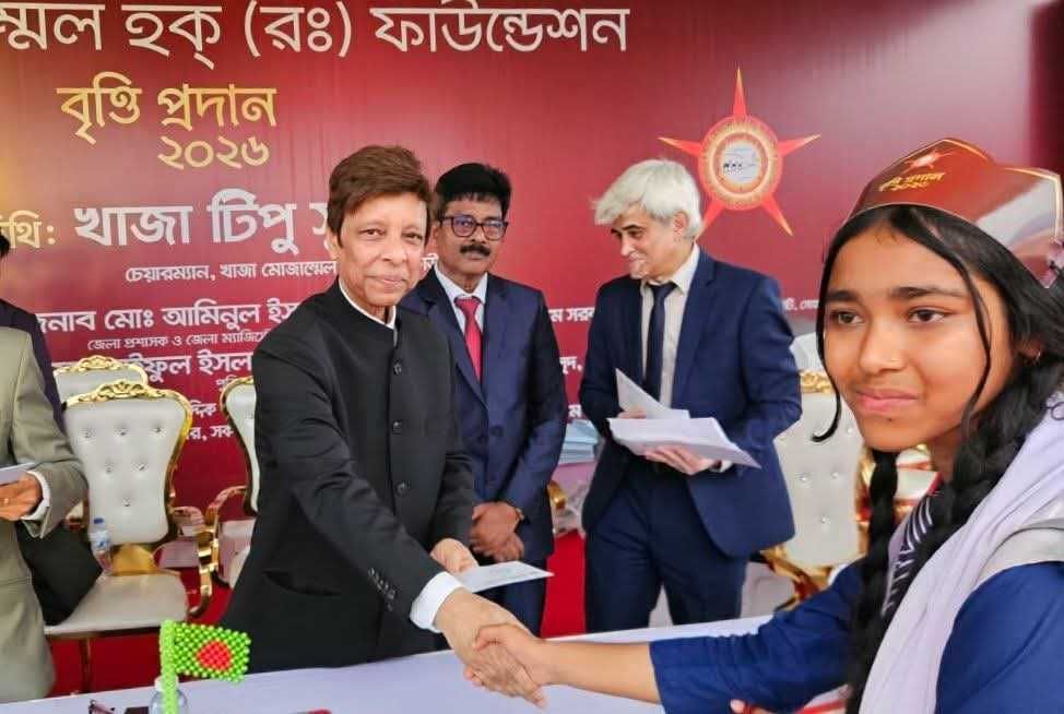 A student receiving her scholarship with a handshake.